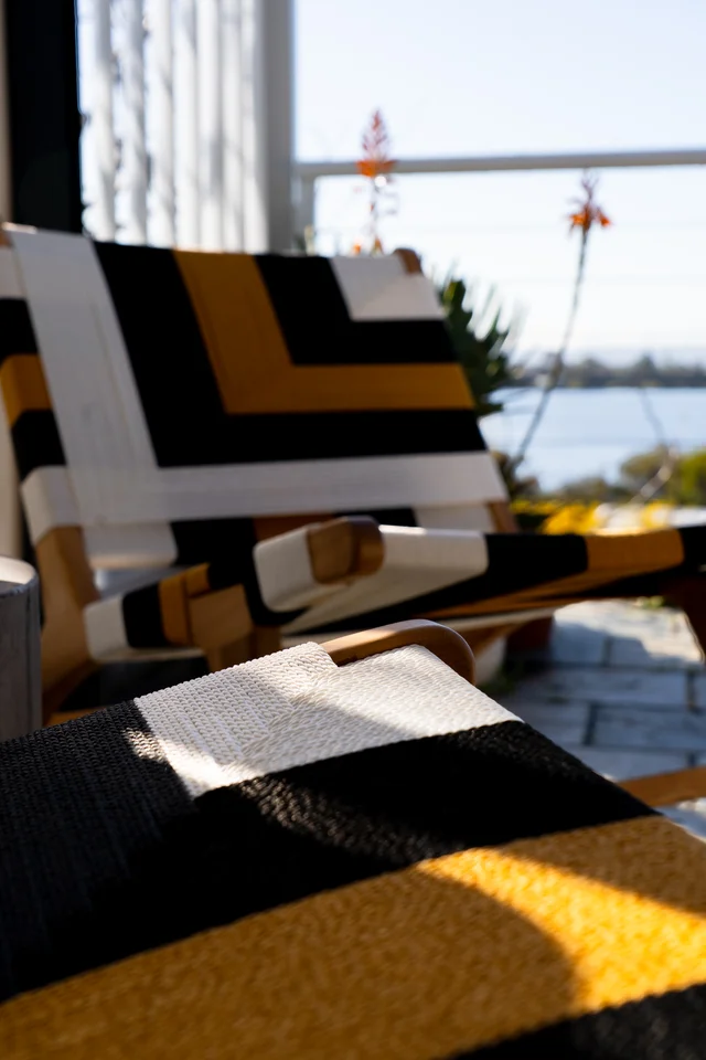 Geometric black, white and yellow woven chair in sunlight.