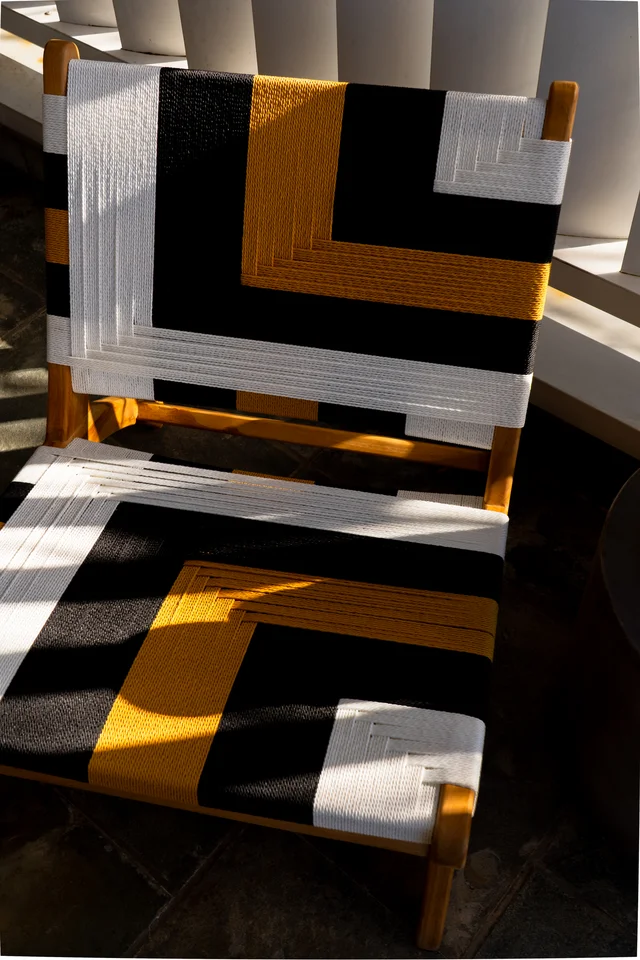 Geometric black, white and yellow woven chair in sunlight.