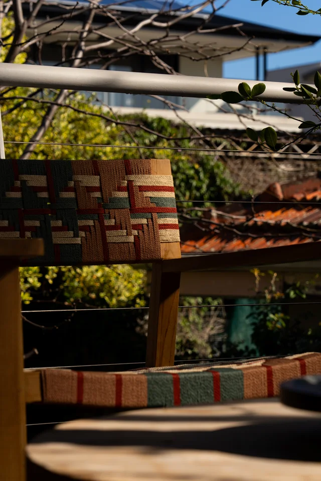 Colourful woven chair details in patterned sunlight and shadow.