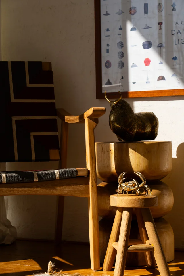 Wooden furniture and sculptural objects beside a wall print.
