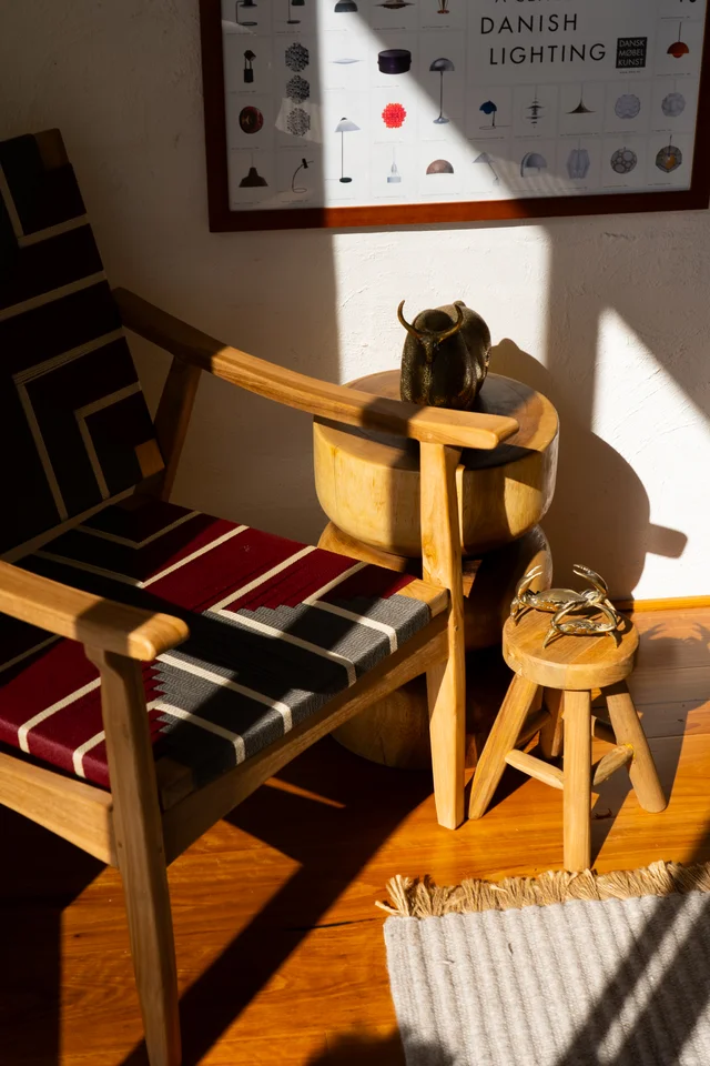 Wooden furniture and sculptural objects beside a wall print.