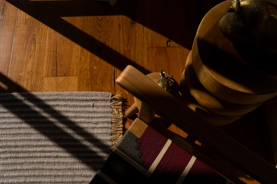 Close-up of wooden furniture and woven upholstery in warm light.