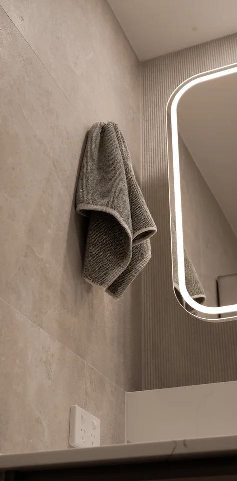 Bathroom towel beside a softly illuminated mirror.