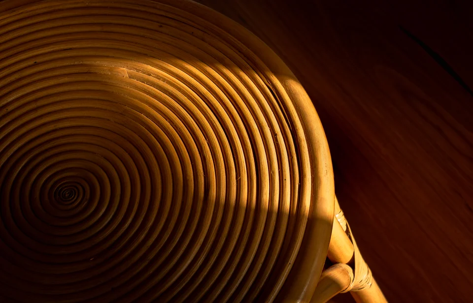 Curved woven wooden seating illuminated by warm sunlight.