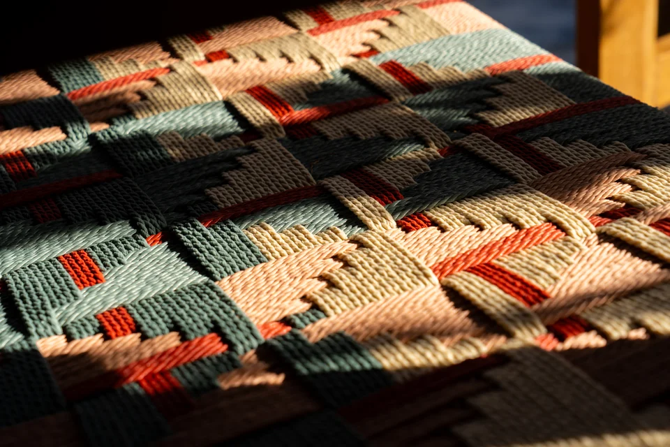 Colourful woven chair details in patterned sunlight and shadow.