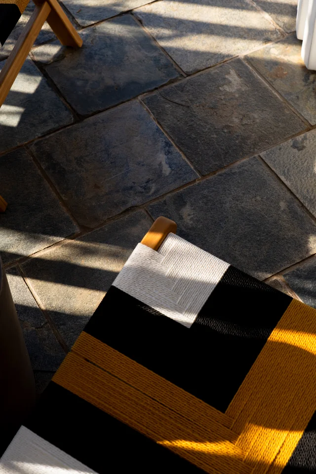 Geometric black, white and yellow woven chair in sunlight.
