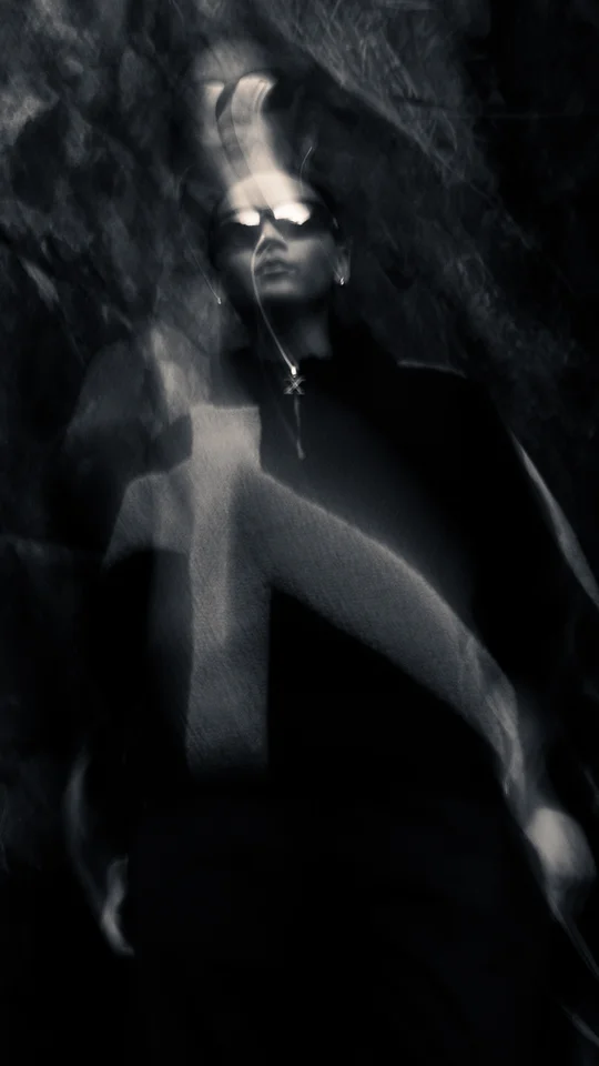 Motion-blurred portrait of a model in dark outerwear against rocks.