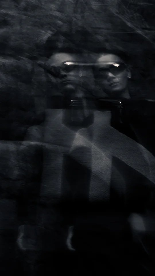 Motion-blurred portrait of a model in dark outerwear against rocks.