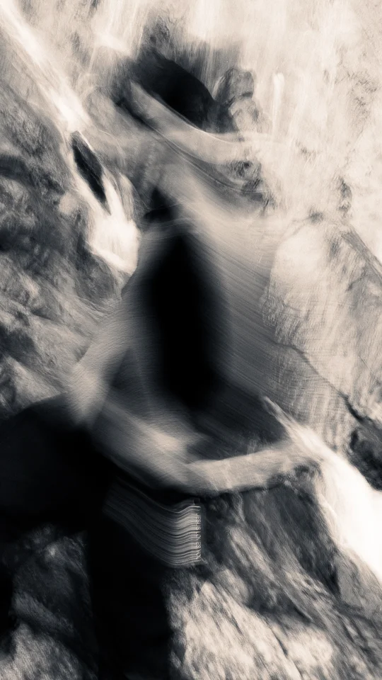Motion-blurred fashion portrait in front of a waterfall.