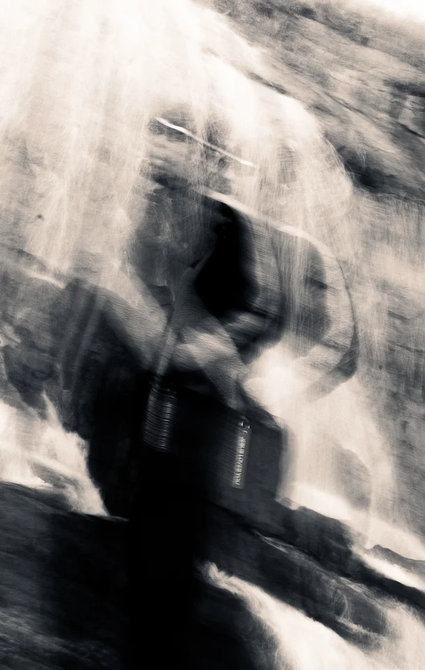 Motion-blurred fashion portrait in front of a waterfall.