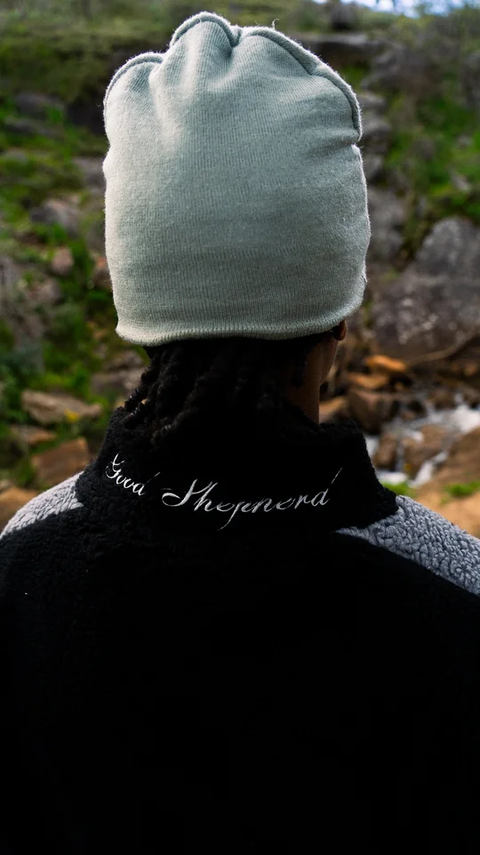 Back detail of a grey beanie and an embroidered black jacket collar.