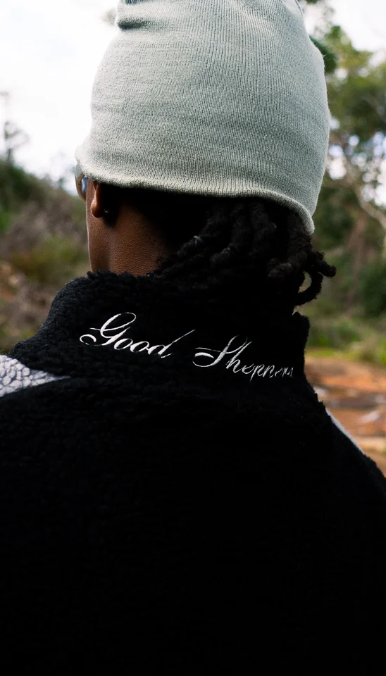 Back detail of a grey beanie and an embroidered black jacket collar.