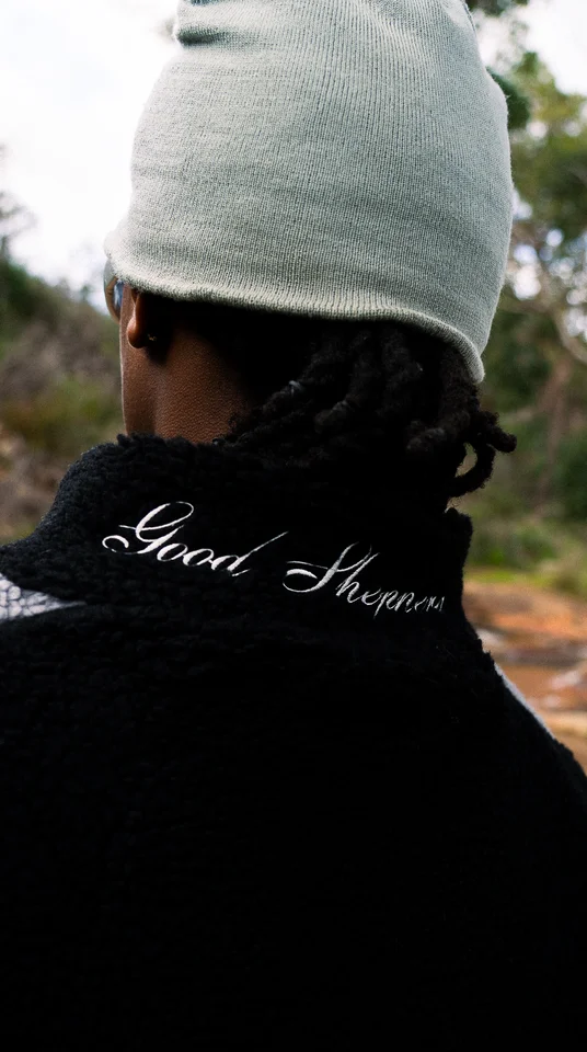 Back detail of a grey beanie and an embroidered black jacket collar.