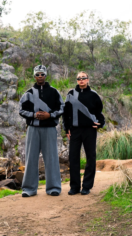 Two models wearing coordinated black and grey jackets outdoors.