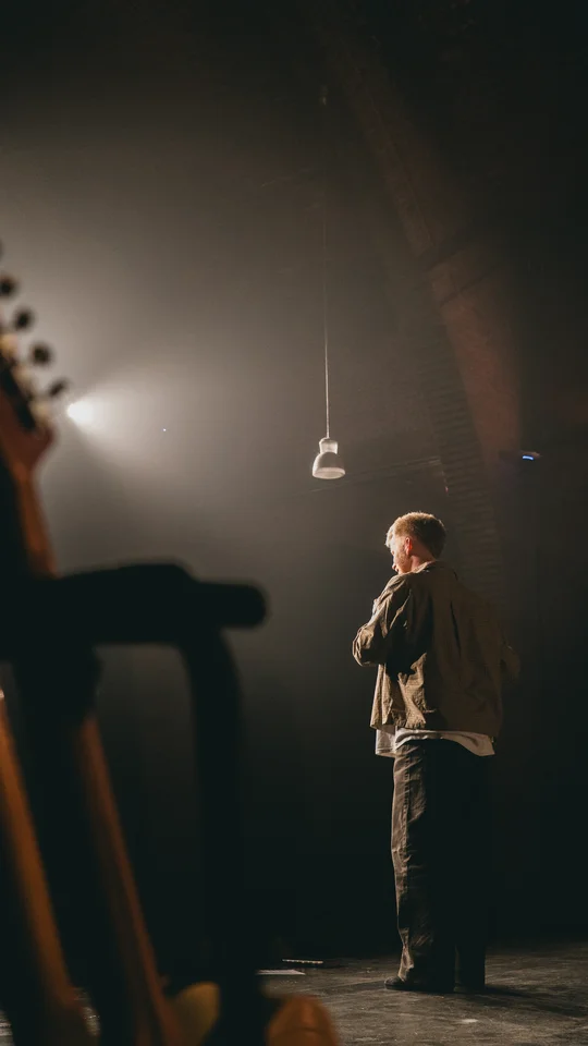 Performer holding a microphone on a dimly lit stage.