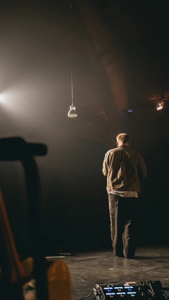 Performer holding a microphone on a dimly lit stage.