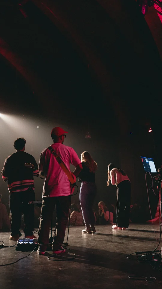 Performers and musical equipment under stage spotlights.