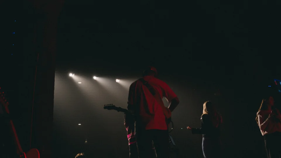 Performers and musical equipment under stage spotlights.