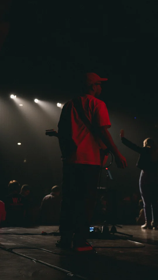 Performers and musical equipment under stage spotlights.